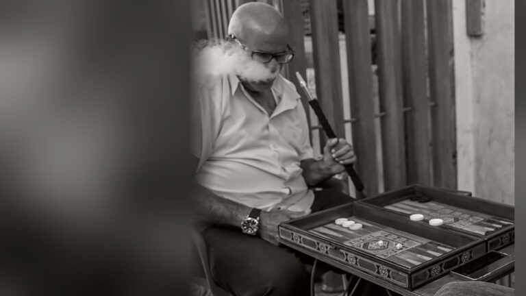 גבר מבוגר משחק שש-בש בשוק